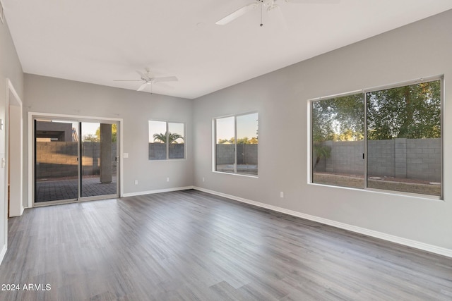 empty room featuring ceiling fan, plenty of natural light, and dark hardwood / wood-style flooring