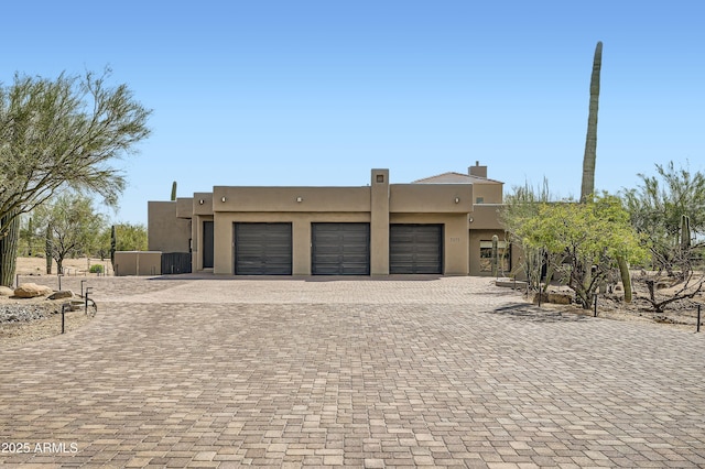 view of front of property featuring an attached garage, a chimney, stucco siding, and driveway