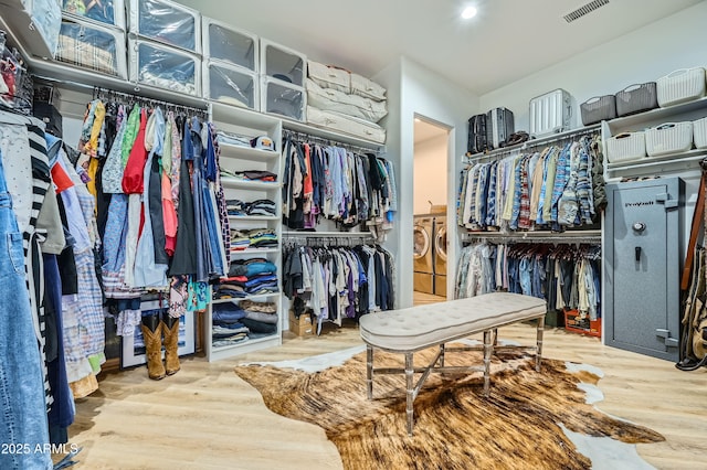 spacious closet with washing machine and dryer, wood finished floors, and visible vents