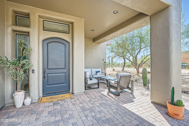 doorway to property with stucco siding, outdoor lounge area, and a patio