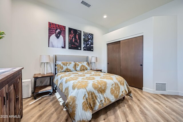 bedroom with a closet, visible vents, and light wood-style flooring