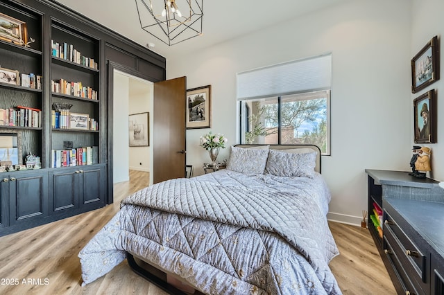 bedroom with baseboards, a notable chandelier, and light wood finished floors