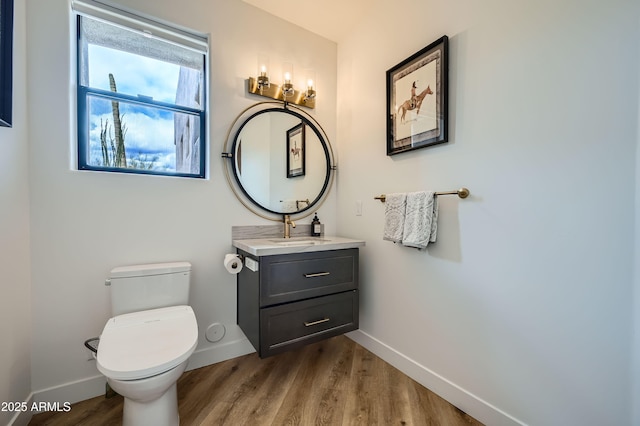bathroom featuring baseboards, toilet, vanity, and wood finished floors