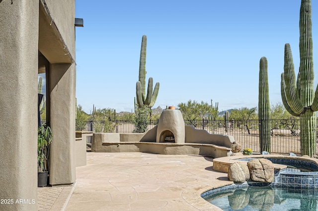 view of patio with fence, a fenced in pool, exterior fireplace, and an in ground hot tub