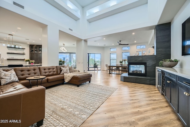 living area with light wood finished floors, visible vents, recessed lighting, and a multi sided fireplace