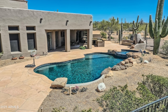 view of pool with a patio area, a pool with connected hot tub, and fence