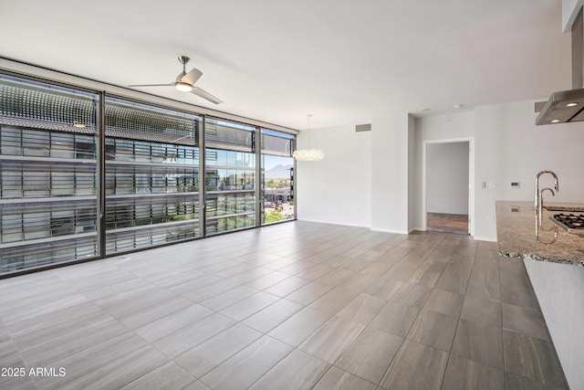 7180 E Kierland Blvd Unit 507, Scottsdale, AZ 85254 - unfurnished living room with a wall of windows, a ceiling fan, and a chandelier