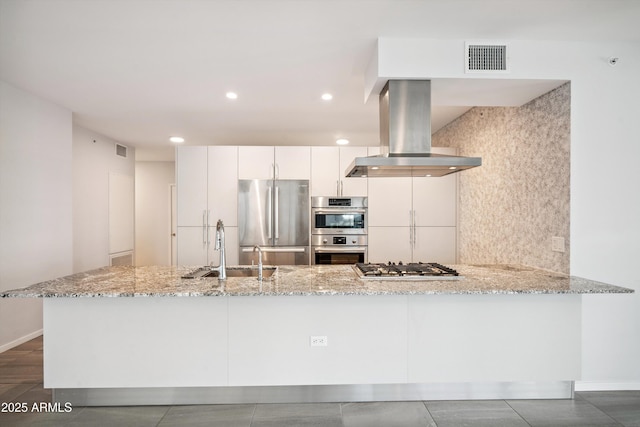 7180 E Kierland Blvd Unit 507, Scottsdale, AZ 85254 - kitchen with appliances with stainless steel finishes, exhaust hood, light stone counters, white cabinetry, and a peninsula