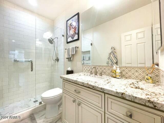 bathroom with vanity, tasteful backsplash, toilet, and walk in shower