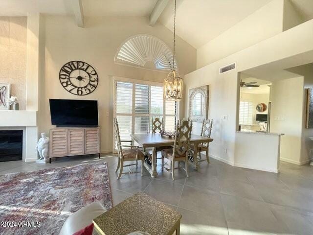 tiled dining space with beamed ceiling, ceiling fan with notable chandelier, and high vaulted ceiling