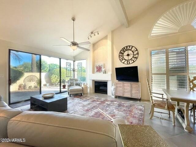 living room featuring a fireplace, ceiling fan, plenty of natural light, and high vaulted ceiling