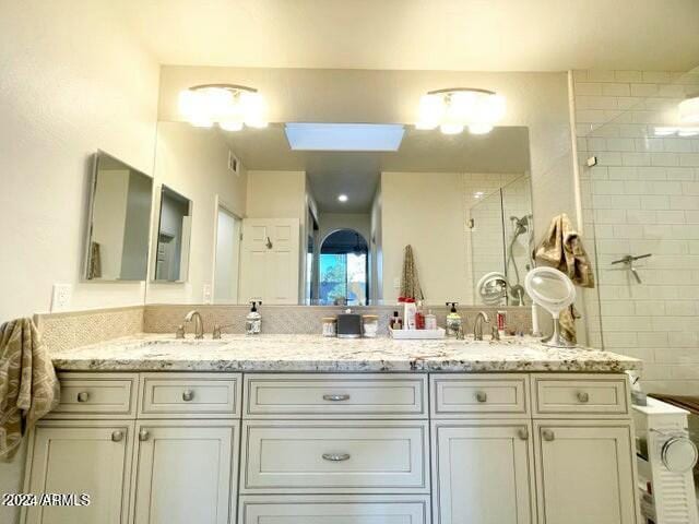 bathroom featuring vanity, a tile shower, and a skylight