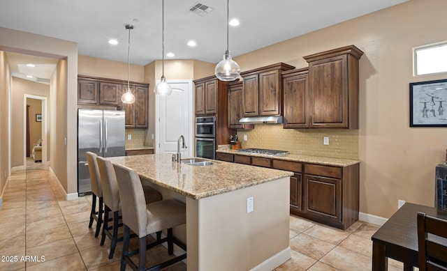 kitchen with stainless steel appliances, a sink, under cabinet range hood, light tile patterned floors, and backsplash