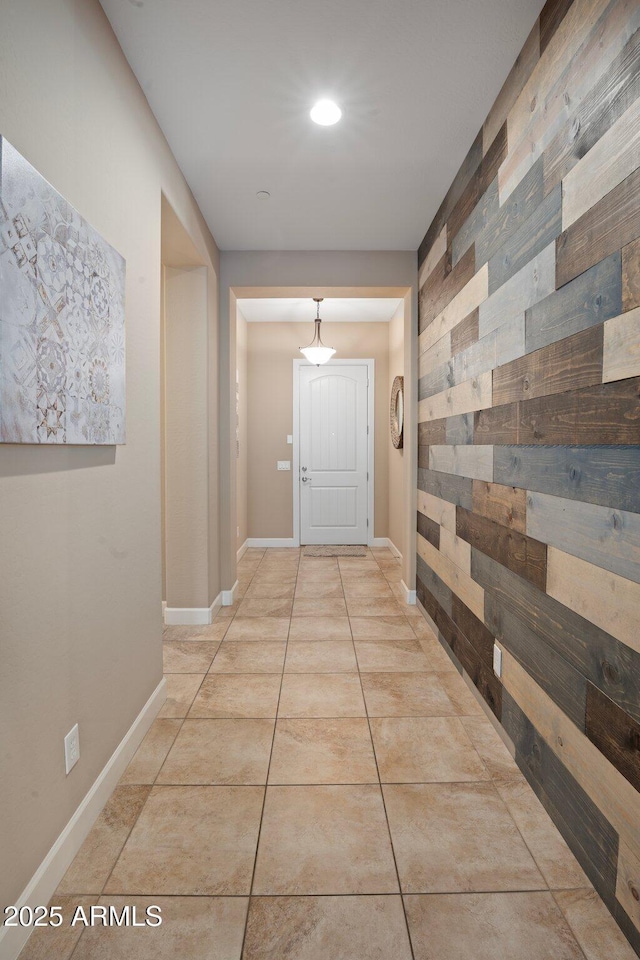 hall featuring wood walls, recessed lighting, light tile patterned flooring, and baseboards