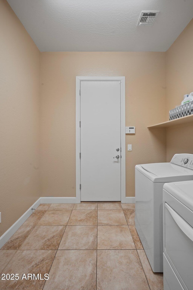 washroom with washing machine and dryer, baseboards, and light tile patterned floors