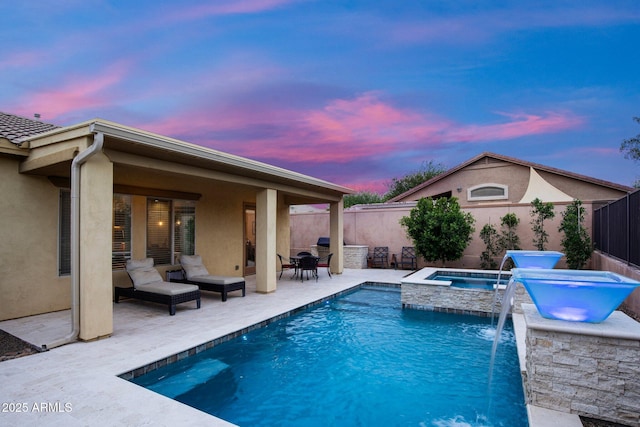 pool at dusk featuring an in-ground hot tub, a patio, and a fenced backyard