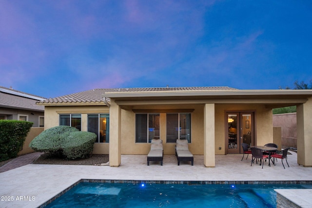 back of property featuring stucco siding, a patio, and an outdoor pool