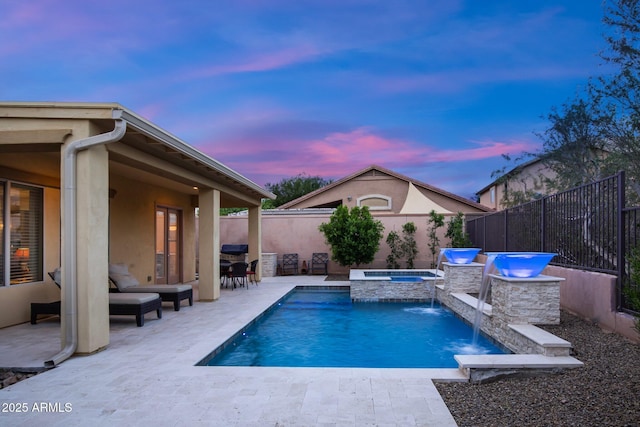 pool at dusk with an in-ground hot tub, a patio area, and a fenced backyard