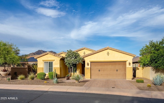 view of front of house with a garage, stucco siding, fence, and decorative driveway