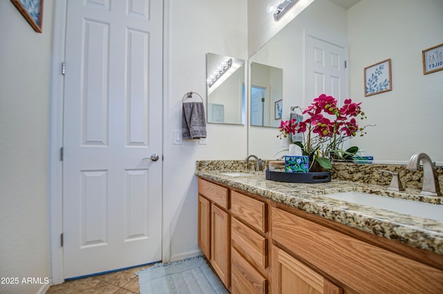 bathroom with double vanity, tile patterned floors, baseboards, and a sink