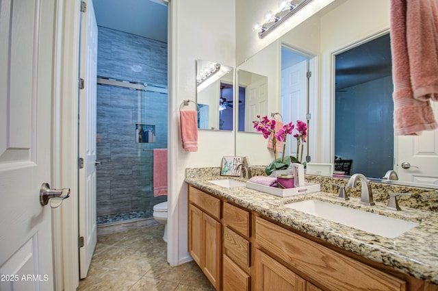 bathroom with a sink, toilet, a stall shower, and double vanity