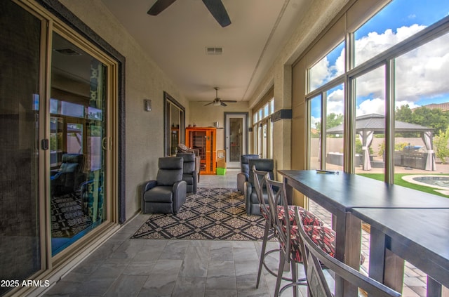 unfurnished sunroom featuring visible vents and ceiling fan