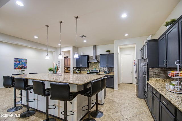 kitchen featuring a breakfast bar area, light stone countertops, visible vents, freestanding refrigerator, and wall chimney exhaust hood