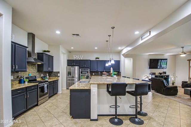 kitchen featuring light stone counters, visible vents, stainless steel appliances, wall chimney exhaust hood, and open floor plan