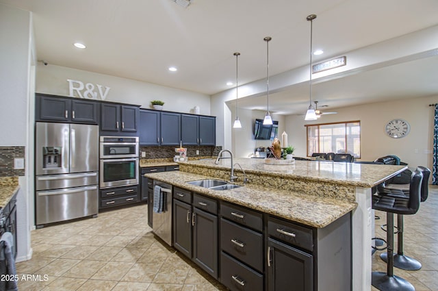 kitchen featuring open floor plan, a breakfast bar, decorative backsplash, stainless steel appliances, and a sink