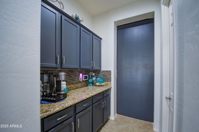 kitchen featuring decorative backsplash, light tile patterned flooring, and light stone countertops