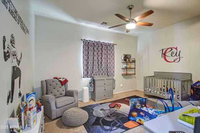 bedroom featuring visible vents, a crib, a ceiling fan, carpet, and baseboards