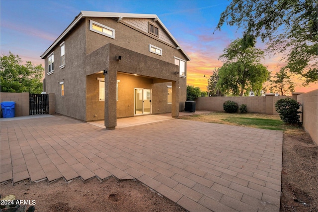 back house at dusk featuring a patio