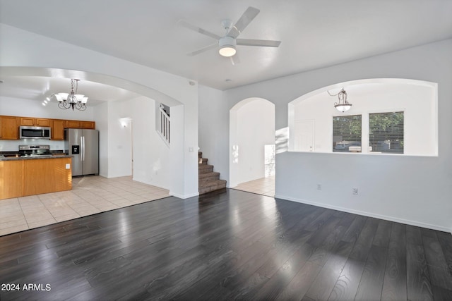 unfurnished living room featuring light hardwood / wood-style flooring and ceiling fan with notable chandelier