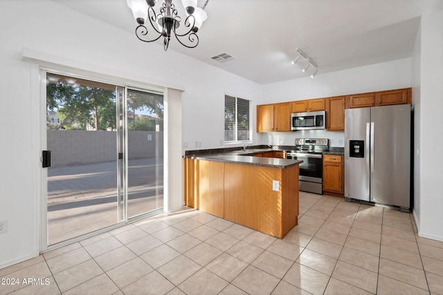 kitchen with kitchen peninsula, stainless steel appliances, light tile patterned floors, and an inviting chandelier