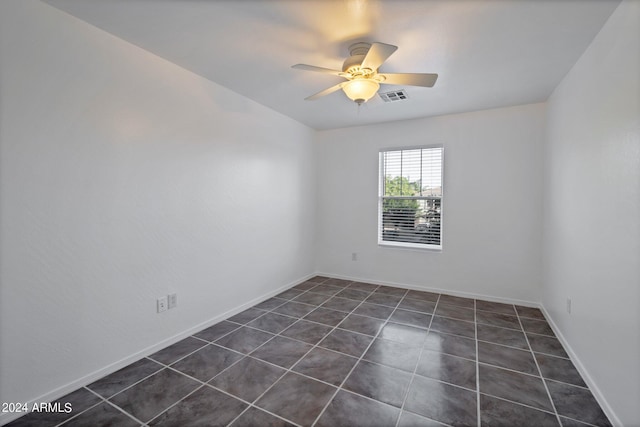 spare room featuring dark tile patterned flooring and ceiling fan