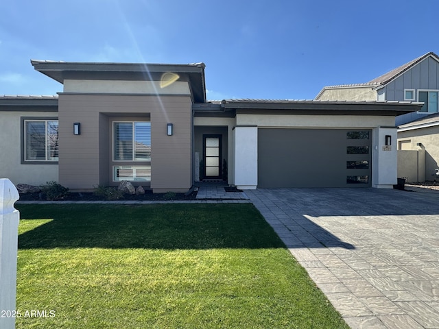 view of front of home featuring a garage, a front lawn, decorative driveway, and stucco siding