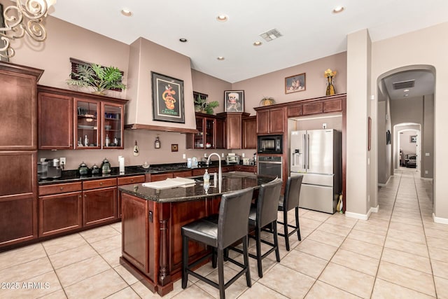 4041 N Silver Ridge Cir, Mesa, AZ 85207 - kitchen featuring stainless steel appliances, arched walkways, light tile patterned floors, a kitchen breakfast bar, and dark stone counters