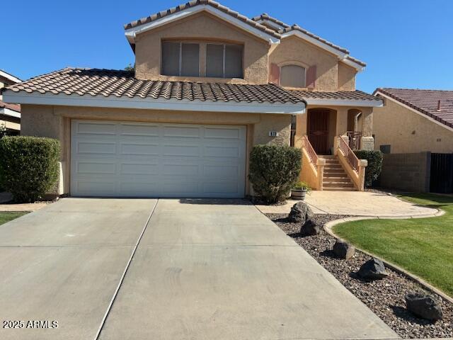 view of front facade featuring a tiled roof, concrete driveway, and stucco siding