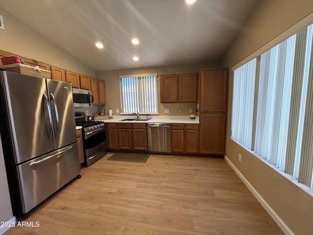 kitchen with stainless steel appliances, a sink, recessed lighting, light wood-style floors, and light countertops