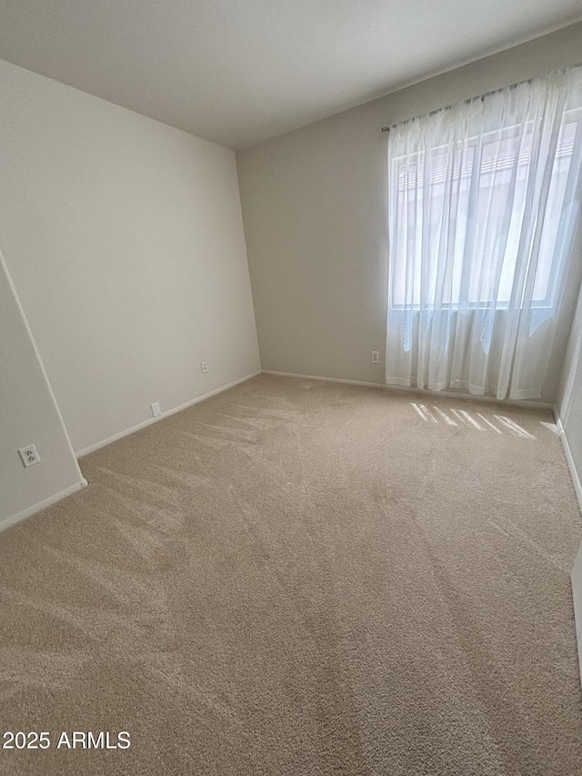 spare room with light carpet and baseboards