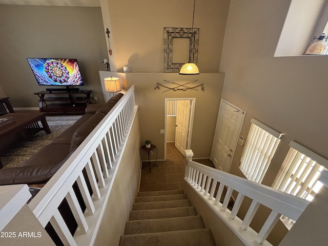 staircase with a towering ceiling and tile patterned floors