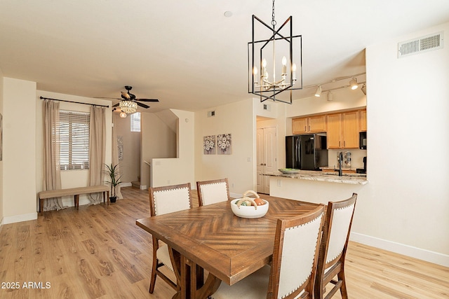 dining room with sink, ceiling fan with notable chandelier, track lighting, and light hardwood / wood-style floors