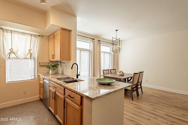 kitchen with sink, hanging light fixtures, stainless steel dishwasher, kitchen peninsula, and light stone countertops