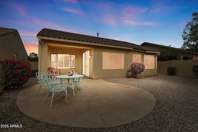 back house at dusk with a patio