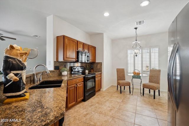 kitchen with sink, dark stone countertops, black appliances, decorative backsplash, and decorative light fixtures