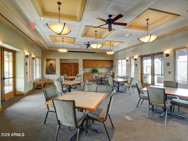 dining space featuring a high ceiling, a raised ceiling, carpet flooring, and french doors