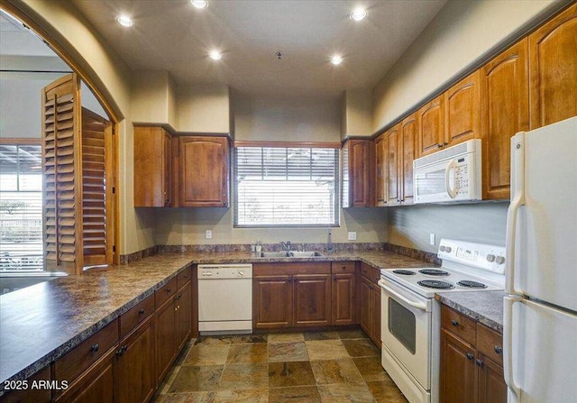 kitchen featuring dark stone countertops, sink, and white appliances