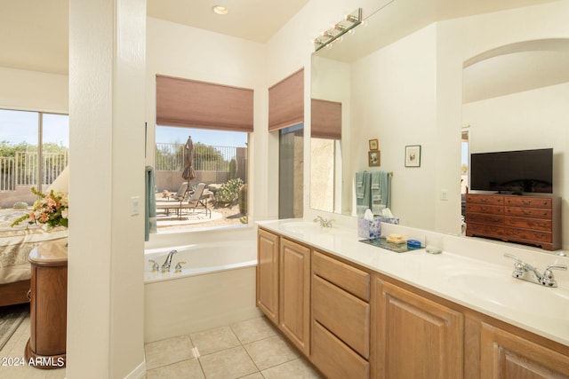 bathroom featuring a wealth of natural light, dual bowl vanity, tile floors, and a bathing tub