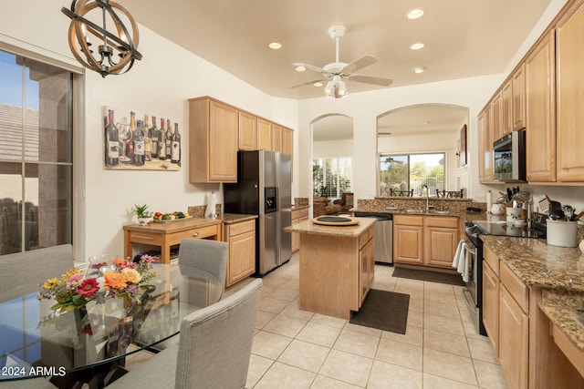 kitchen featuring appliances with stainless steel finishes, a kitchen island, ceiling fan, sink, and light tile floors