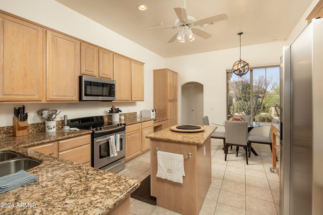 kitchen featuring light tile flooring, dark stone countertops, stainless steel appliances, and hanging light fixtures